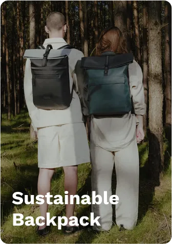 Gray and black sustainable backpack with roll-top design, worn by a person, and a green sustainable backpack, worn by another person, standing in a forest. Reply