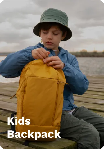 Yellow kids’ backpack with adjustable straps, worn by a child on a wooden dock by the water, under a cloudy sky.